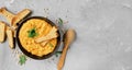 Pea soup with vegetables and spices in a clay bowl, next to a wooden spoon. Top view of hot yellow pea soup, focusing on the top