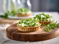 Pea tartlets with fresh goat\'s cheese, decorated with peas on a wooden cutting board