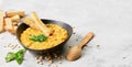 Pea yellow soup with vegetables and spices in a clay bowl, next to a wooden spoon. Close-up, selective focus on a traditional