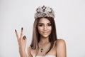 Peace. Beauty queen girl with crown, princess on white gray background, shows victory two 2 sign gesture with fingers hand and Royalty Free Stock Photo