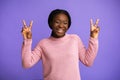 Peace. Joyful Black Young Woman Gesturing V-Sing And Laughing Over Purple Background