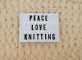 PEACE LOVE KNITTING word on lightbox on knit background. Cozy compozition. Knit WOOL background.