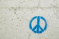 Peace and love symbol painted in blue on a gray concrete wall Royalty Free Stock Photo