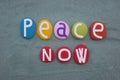 Peace now, creative slogan composed with multi colored stone letters over green sand Royalty Free Stock Photo