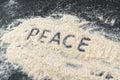 PEACE text written on white sand