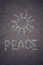 Peace word and sun symbol on the sand - toned photo. Royalty Free Stock Photo