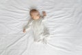 Peaceful adorable baby in bodysuit sleeping on double bed