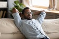 Peaceful African American man wearing glasses relaxing on cozy couch Royalty Free Stock Photo