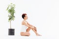 Peaceful african american woman sitting near small tree in pot Royalty Free Stock Photo