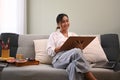 Peaceful asian woman paints picture with watercolor on couch at cozy home. Art, creative hobby and leisure activity Royalty Free Stock Photo