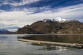 Peaceful autumn landscape wooden pier on a lake shore line with moody scenic view of mountain snowy peak October fall season day Royalty Free Stock Photo