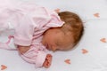 Peaceful baby lying on a bed with heart while sleeping in a bright room. The baby girl is 15 days old Royalty Free Stock Photo