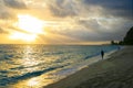 Peaceful beach walk on the sunset after tropical storm when shin sun rays opening the dark dramatic cloudy sky Royalty Free Stock Photo