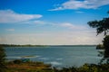 Peaceful blue lake with green grass and blue sky background. Beautiful blue sky and clouds over the reservoir. Rafting activity i