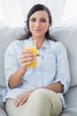 Peaceful brunette offering orange juice to camera