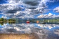 Peaceful calm lake with red orange and blue sailing boats in HDR Ullswater The English Lakes