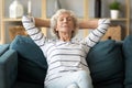 Peaceful calm older woman leaning back on couch