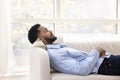 Peaceful calm young African American man lying on white couch Royalty Free Stock Photo