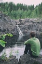 Peaceful and calmness scenic view. Man hiker traveller sitting near mountain waterfall. Active person outdoor mindfulness living