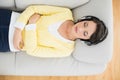 Peaceful casual brunette in yellow cardigan listening to music with headphones