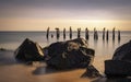 Seascape with rustic rocks and pilings of ruined piers on tropical beach