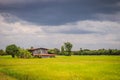 A peaceful cottage on green rice farm with dark stormy sky background. Tranquilly green rice field and farmer hut under calm sky