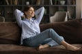 Dreamy female teenager sit barefoot on couch at living room Royalty Free Stock Photo