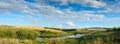 Sunny summer panorama with river,golden wheat fields,green hills and beautiful fluffy clouds in blue sky at sunset. Royalty Free Stock Photo