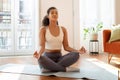 Peaceful fitness lady meditating on yoga mat sitting indoors