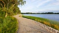 A peaceful footpath along the coast of a lake during sunset in summer with beautiful green vegetation Royalty Free Stock Photo