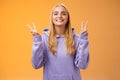 Peaceful glad attractive blond european young female college student in hoodie smiling friendly make peace victory