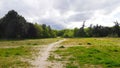 Green Plain with Forest Path Under a Stormy Sky in Parc de Vincennes Royalty Free Stock Photo