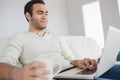 Peaceful handsome man having coffee while using his laptop Royalty Free Stock Photo