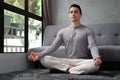 Peaceful handsome man practicing yoga in living room