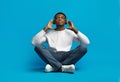 Peaceful handsome young african guy listening to music on blue Royalty Free Stock Photo