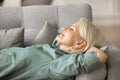 Peaceful happy elderly woman resting on soft comfortable sofa Royalty Free Stock Photo