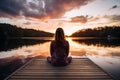 Peaceful lifestyle shot of woman sitting on dock at sunset on Lake