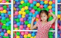 Peaceful little Asian girl catching cage of playground colorful toy ball with looking out