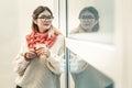 Peaceful long-haired girl in wireless headphones looking outside the window