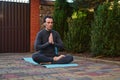 Peaceful man athlete, a yogi meditating in lotus pose, sitting barefoot on a fitness mat. Yoga practice. Mindfulness