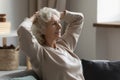 Hoary woman relaxing on couch with folded hands behind head. Royalty Free Stock Photo