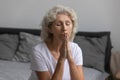 Peaceful middle aged woman praying God in morning after wake up.