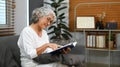 Peaceful middle aged woman resting on couch and reading interesting book, enjoying leisure weekend time at home Royalty Free Stock Photo