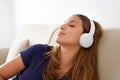 Peaceful millennial girl lie on comfort couch wearing wireless headphones enjoy good meditative music. Serene young woman in Royalty Free Stock Photo