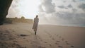 Peaceful model walking sand beach leaving footprints. Travel woman turning back Royalty Free Stock Photo