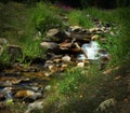 Peaceful mountain stream / brook with a cascade of water tumbling over rocks, flowing into the foreground of the picture. Royalty Free Stock Photo