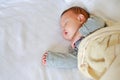 Peaceful newborn Asian baby boy sleeping on bed with the blanket Royalty Free Stock Photo