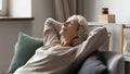 Peaceful older 60s lady resting on comfortable couch Royalty Free Stock Photo