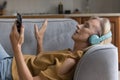 Peaceful older woman listen playlist on smartphone through wireless headphones