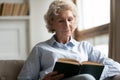 Peaceful older woman reading interesting bestseller paper book. Royalty Free Stock Photo